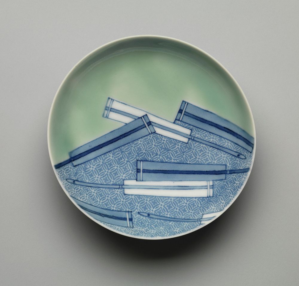 Shallow dish on low foot; blue and white design of folded fans in lower half, with ornate brocade background; pale green…