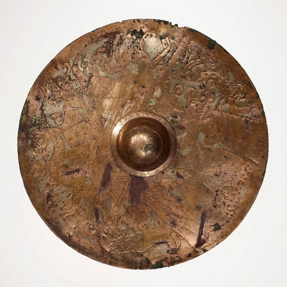 flat, round disc with domed protrusion at center; incised with figures, birds, animals and designs; mounted on black cloth…
