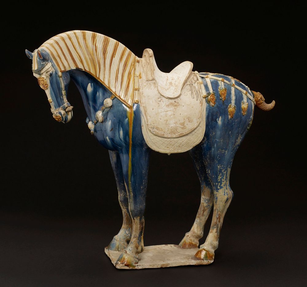 Horse with long mane and clipped tail. ca 725 A.D. Glazed pottery tomb figure, one of a pair, on a flat base. The decoration…