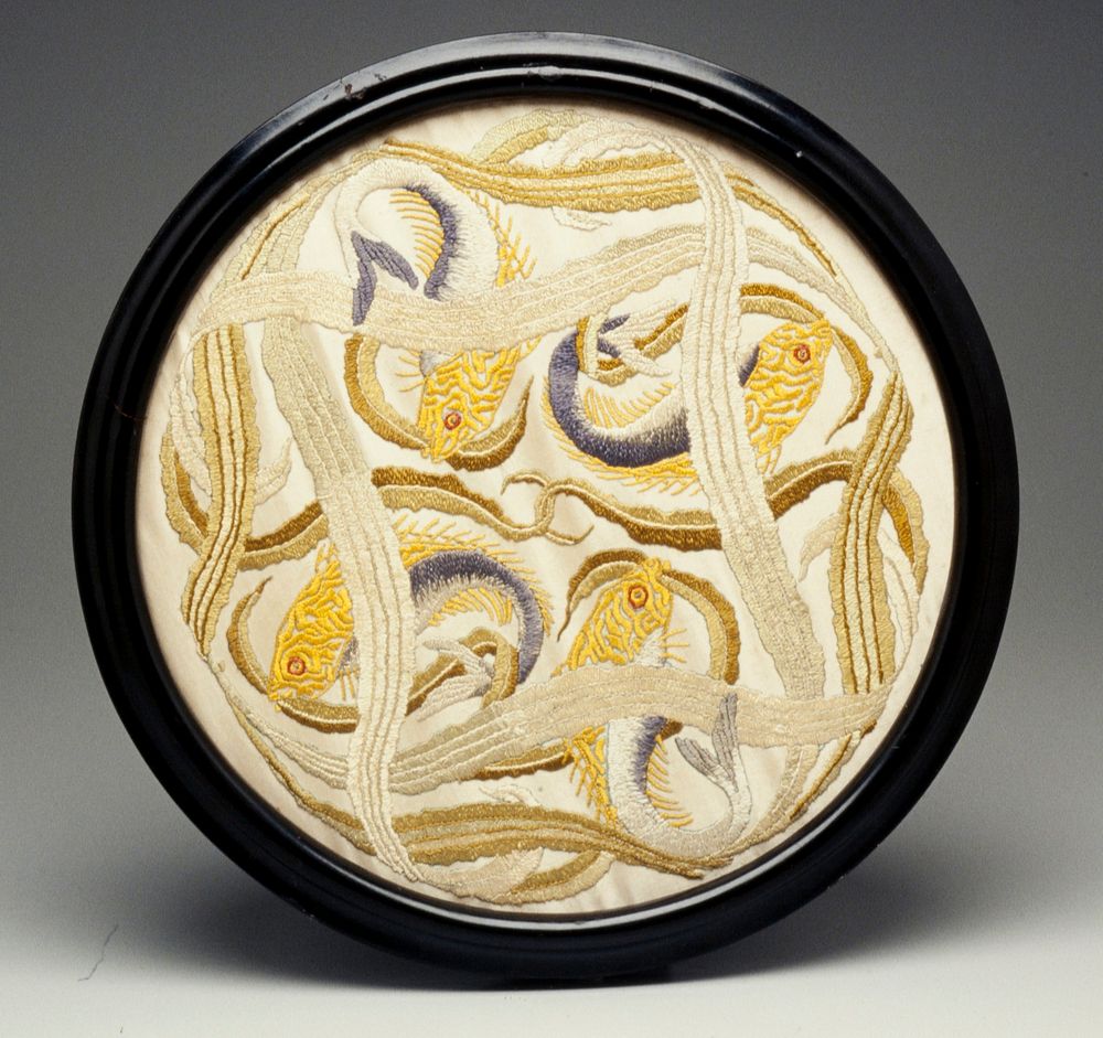 circular framed embroidery; four gold, blue and grey fish feeding on a patch of intertwining seaweed on a cream ground; was…