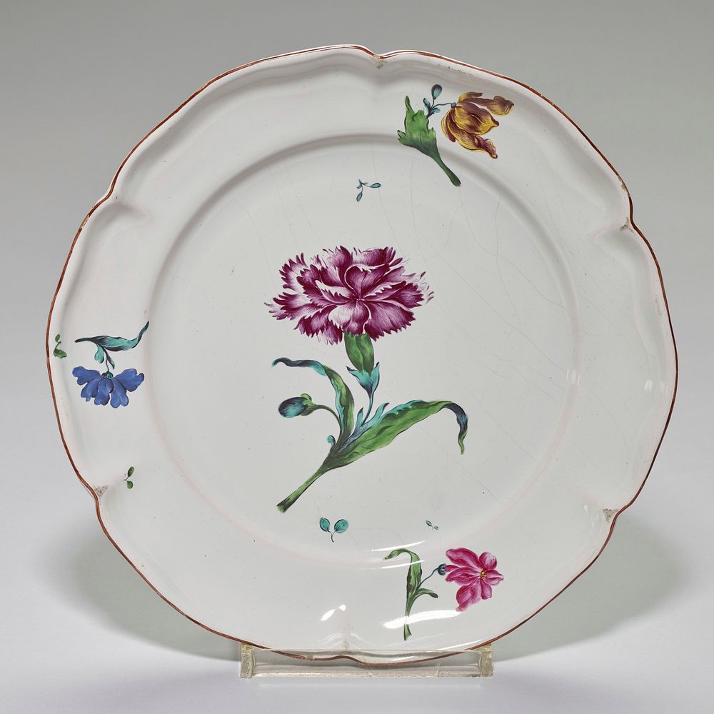 faience plate; rather deep, hexagonal-lobed shape; brown glaze on edge; center contains one large carnation painted in deep…