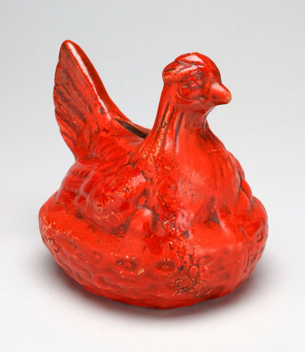 ceramic bank in the form of a hen on a nest; covered in red glaze, hen's head is cocked and lookng proper left;. Original…