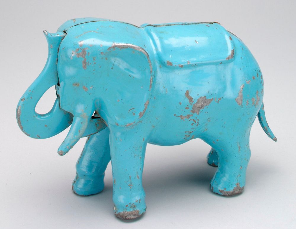 light blue standing elephant with trunk to forehead; press tail in, trunk moves forward to deposit coin in forehead; screw…