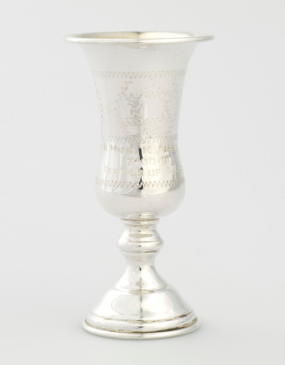 small footed cup; cup has rounded bottom and flares outward at lip; decorated with incised zigzag designs; engraved…