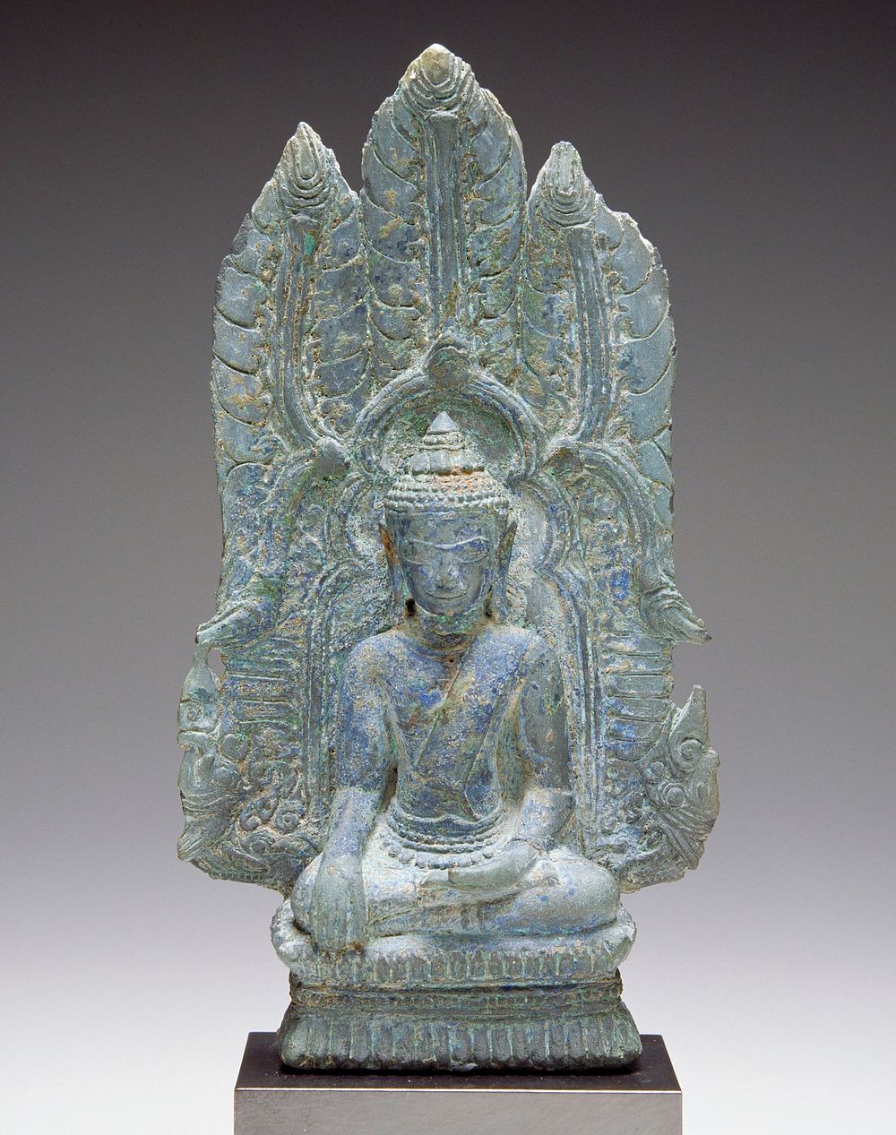 seated Buddha with PL hand palm up on lap and PR hand on knee; organic, leaflike designs on back of throne; attached to…