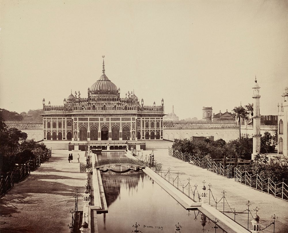 central domed building with spires and arches; canal center foreground to building; bridge across canal; three figures at L…