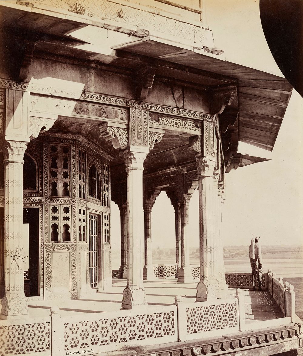 figure on a balcony of an elaborate building with geometric floral designs in tile and openwork; floral panels on inner…