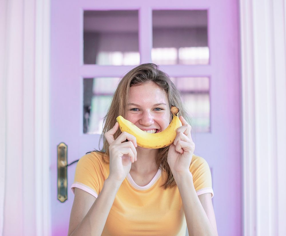 Happy Caucasian woman with banana on her face