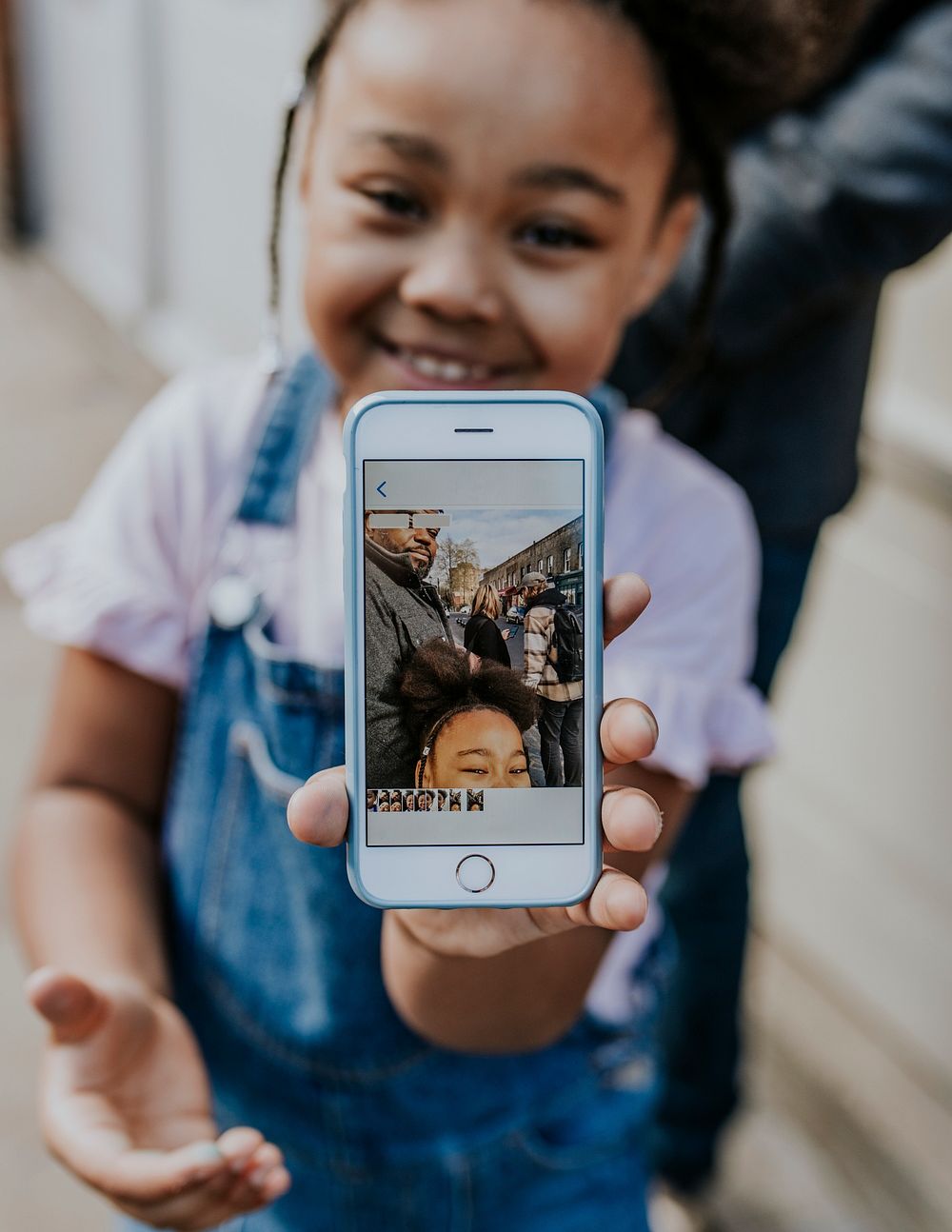 Little girl showing family selfie on smartphone