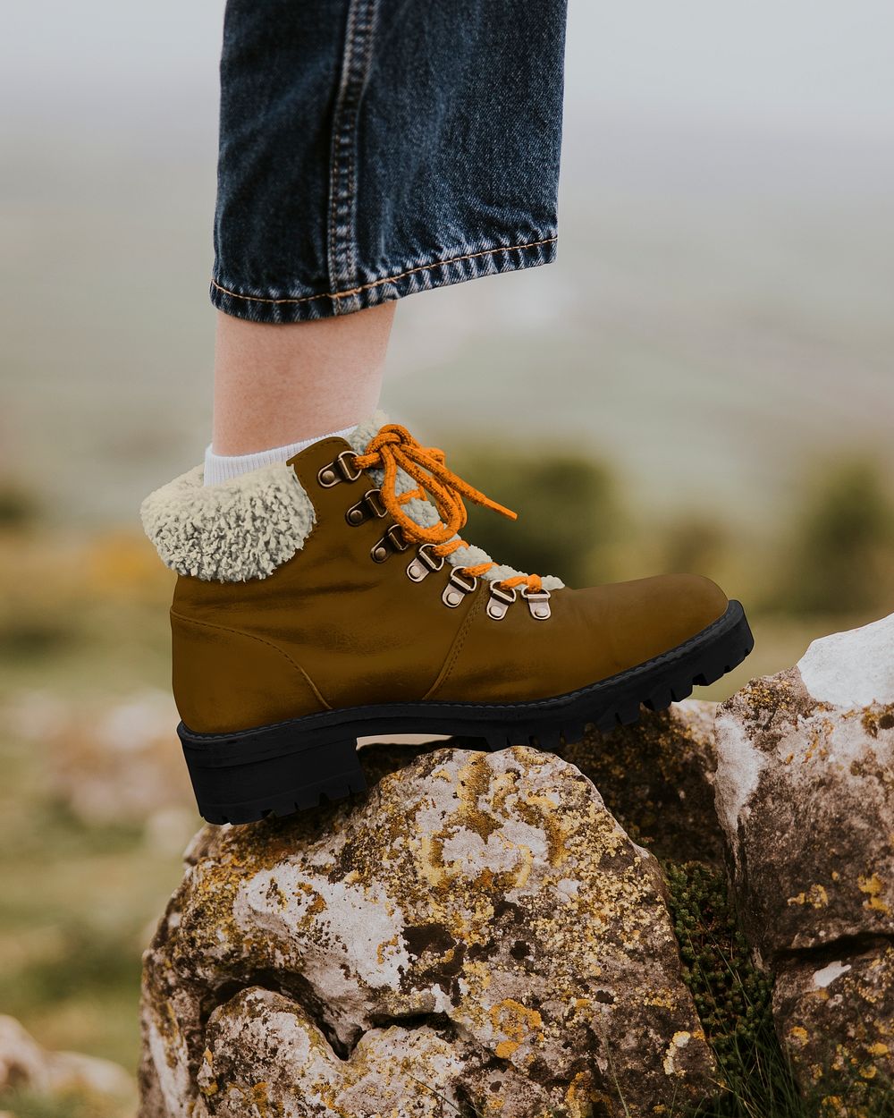 Closeup woman's brown boot on rock, outdoor photo