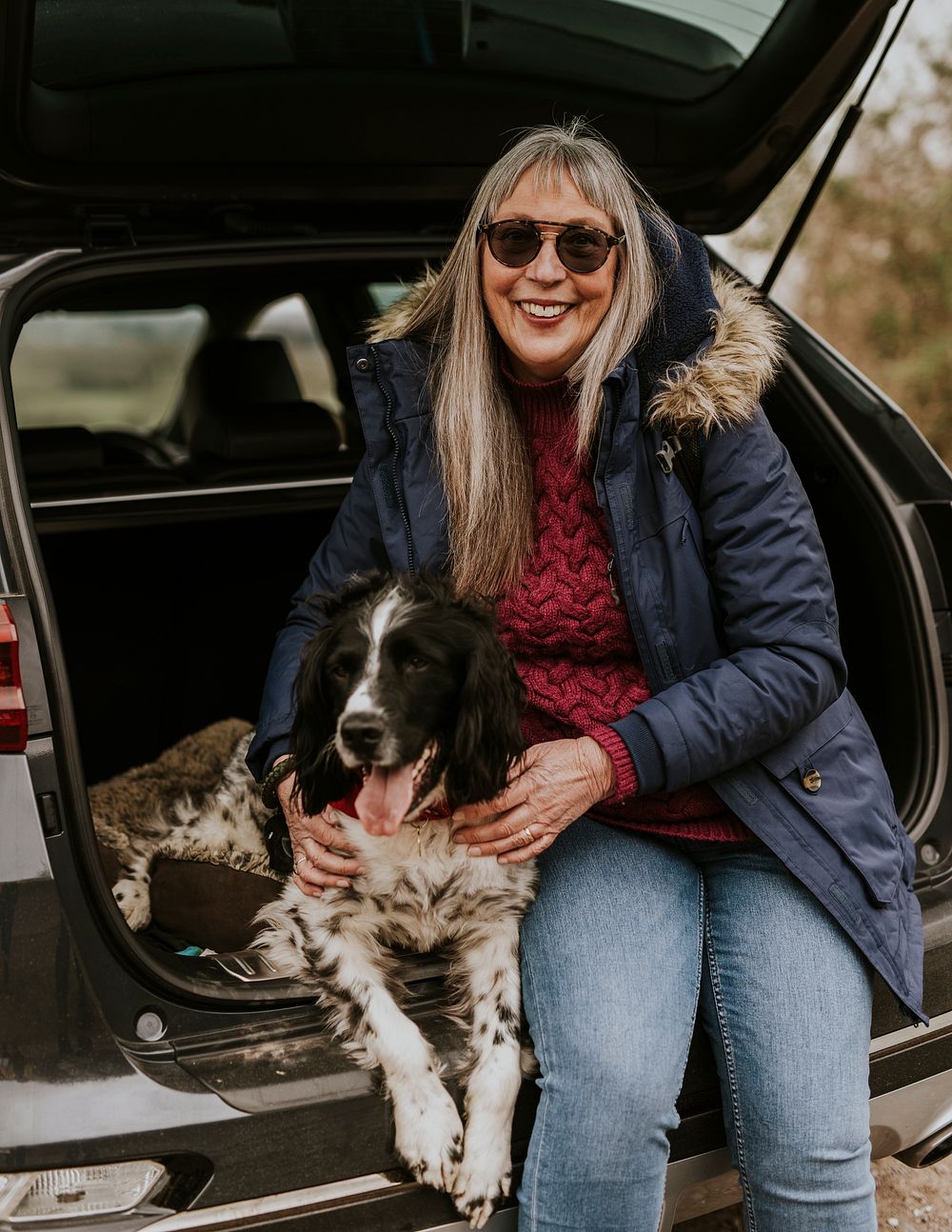 Woman and dog sitting at the back of her car