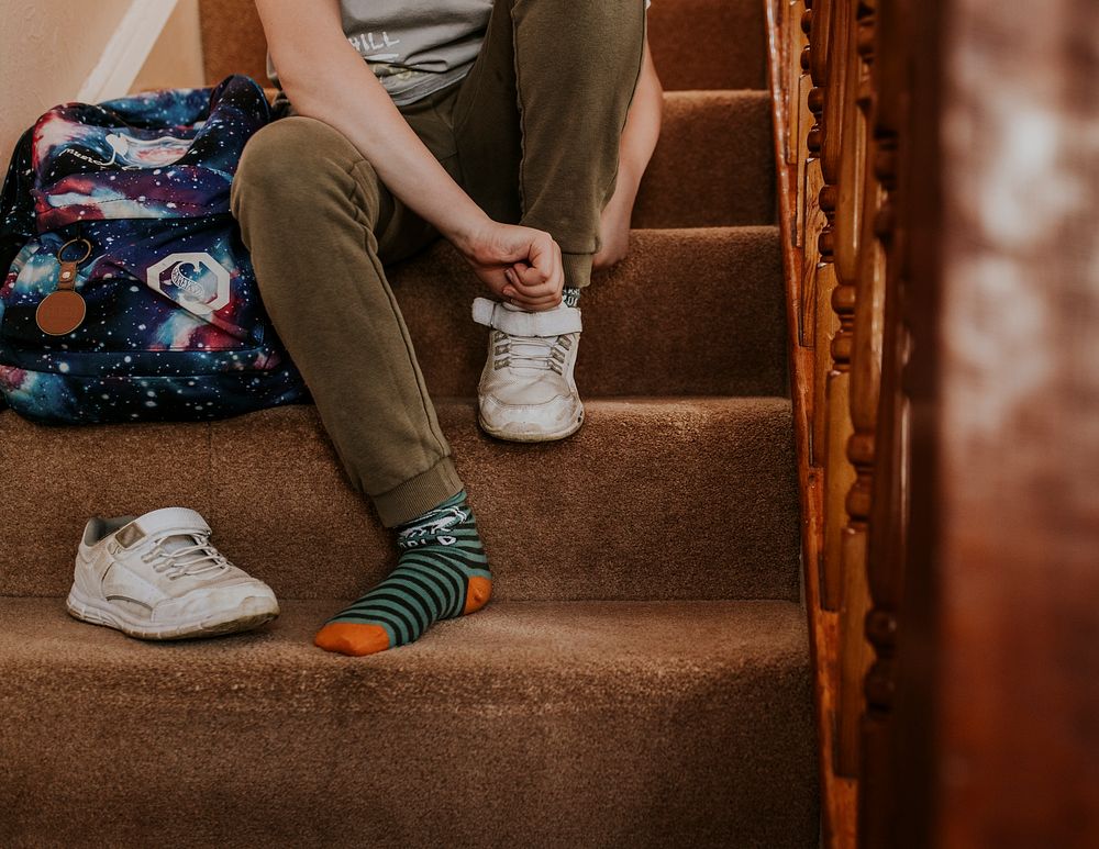 Boy putting on shoe, getting ready for school