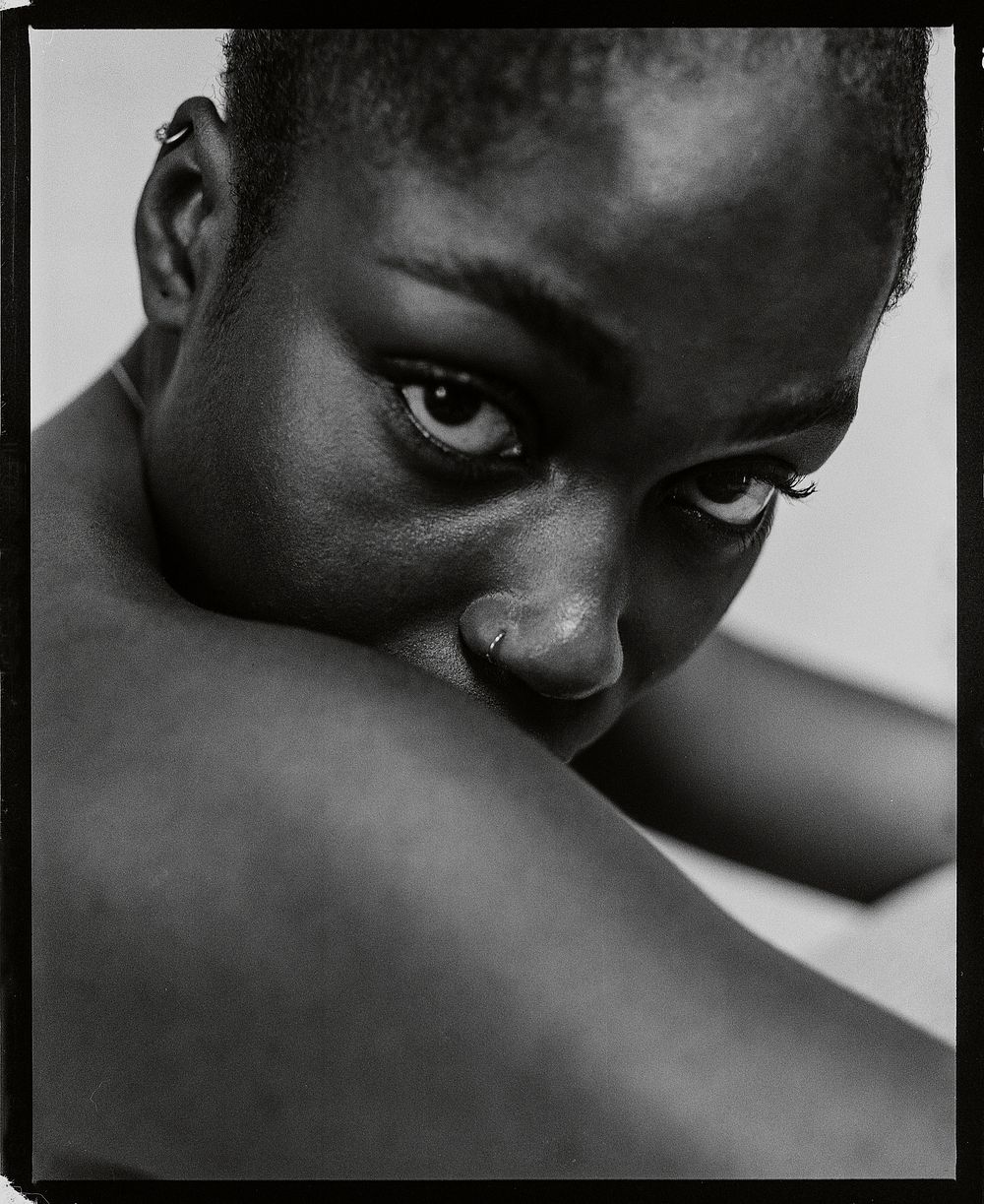 African woman looking over bare shoulder, black and white photo