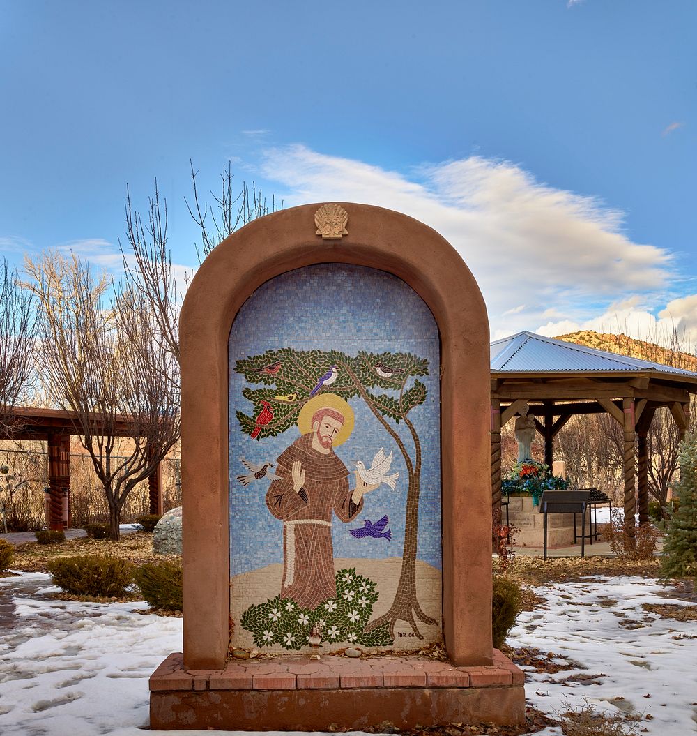                         A biblical mosaic along a pathway containing shrines and stations of the cross behind the El…