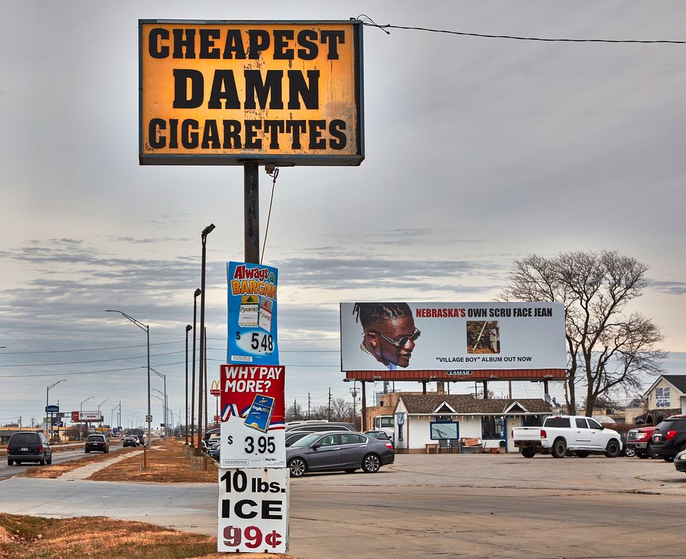                        "Cheapest Damn Cigarettes" is not only a promotional slogan on a sign outside a roadside tobacco and…