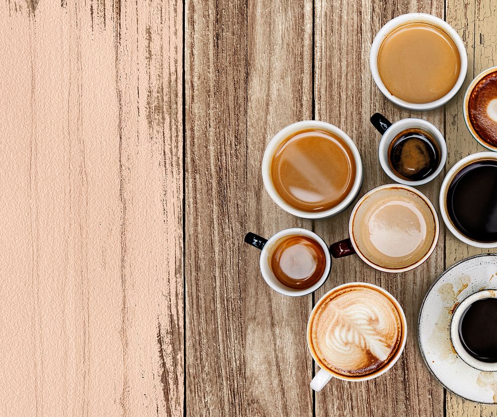 Mixed coffee cups on a pastel pink and brown wooden panel