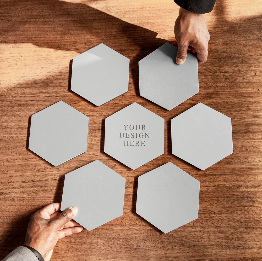 Hands arranging connected hexagon cut out papers