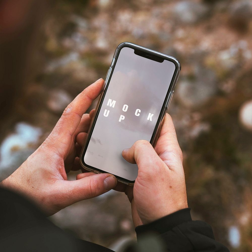 Hands holding a smartphone outdoors mockup