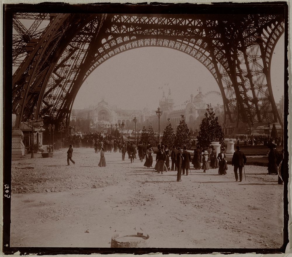 Exposition Universelle de 1900 : personnages sous La tour Eiffel, et perspective du Champ-de-Mars, Paris (VIIème arr.).…