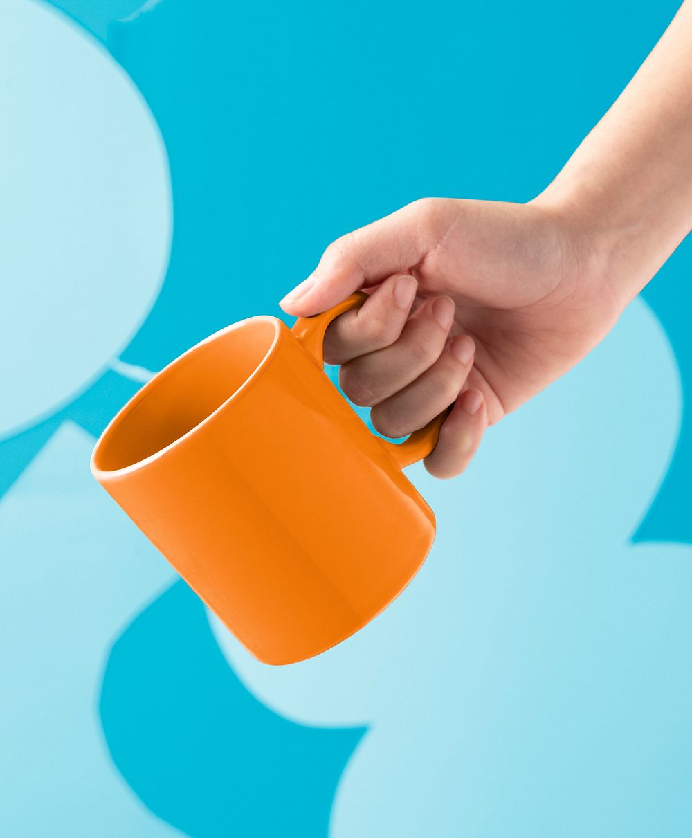 Hand holding orange coffee mug