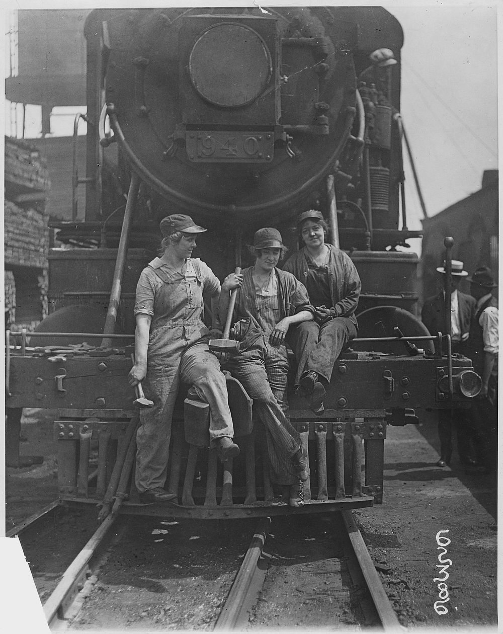 "Busch [Bush] Terminal. Women Laborers Seated on Front of Engine in Railroad Yard. War Industries Picture." Original public…