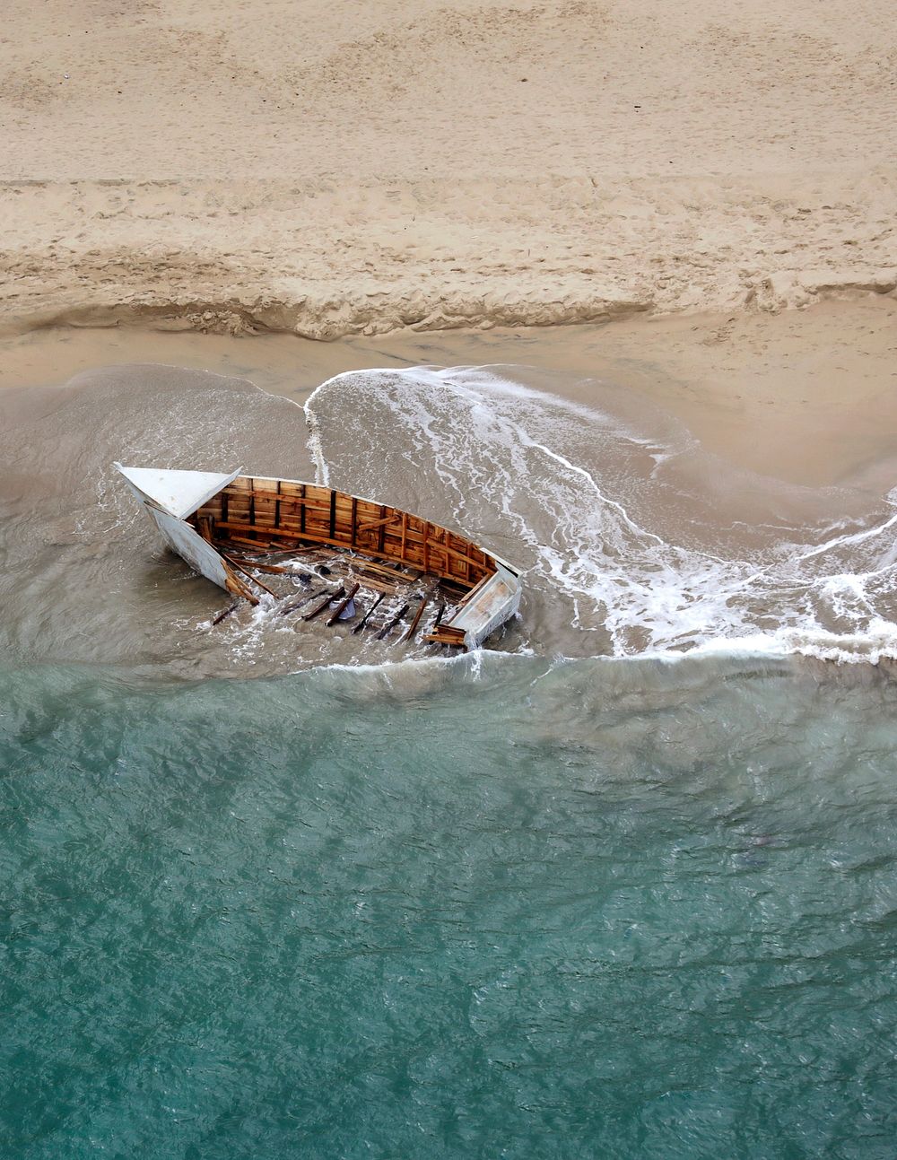 A small, makeshift boat, or "yola," sits awash on a remote beach near Aguadilla, Puerto Rico, April 3, 2019.