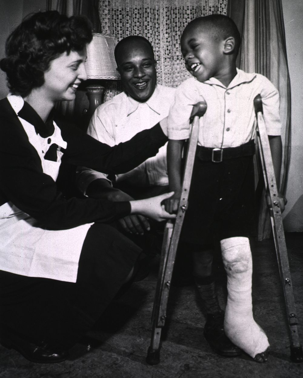 Public Health nurse assists in the healing process. A young boy, on crutches, his left leg in a cast, takes first steps with…