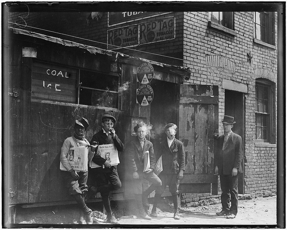 11:00 A.M. Newsies at Skeeter's Branch. They were all smoking. St. Louis, Mo, May 1910. Photographer: Hine, Lewis. Original…