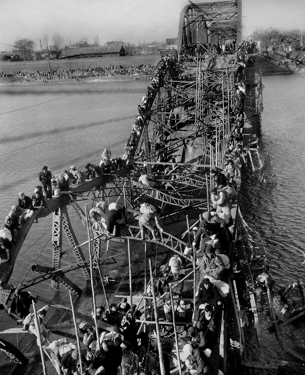 "Flight of Refugees Across Wrecked Bridge in Korea", photograph of refugees fleeing Pyongyang during the Korean War across a…