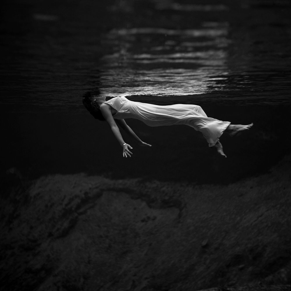 Underwater view of a woman, wearing a long gown, floating in water. Photograph by Toni Frissell at Weeki Wachee Springs…