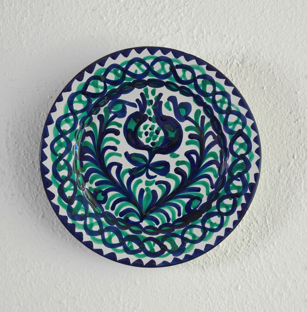 A plate on a wall, pomegranate and colors typical of Granada, Spain.