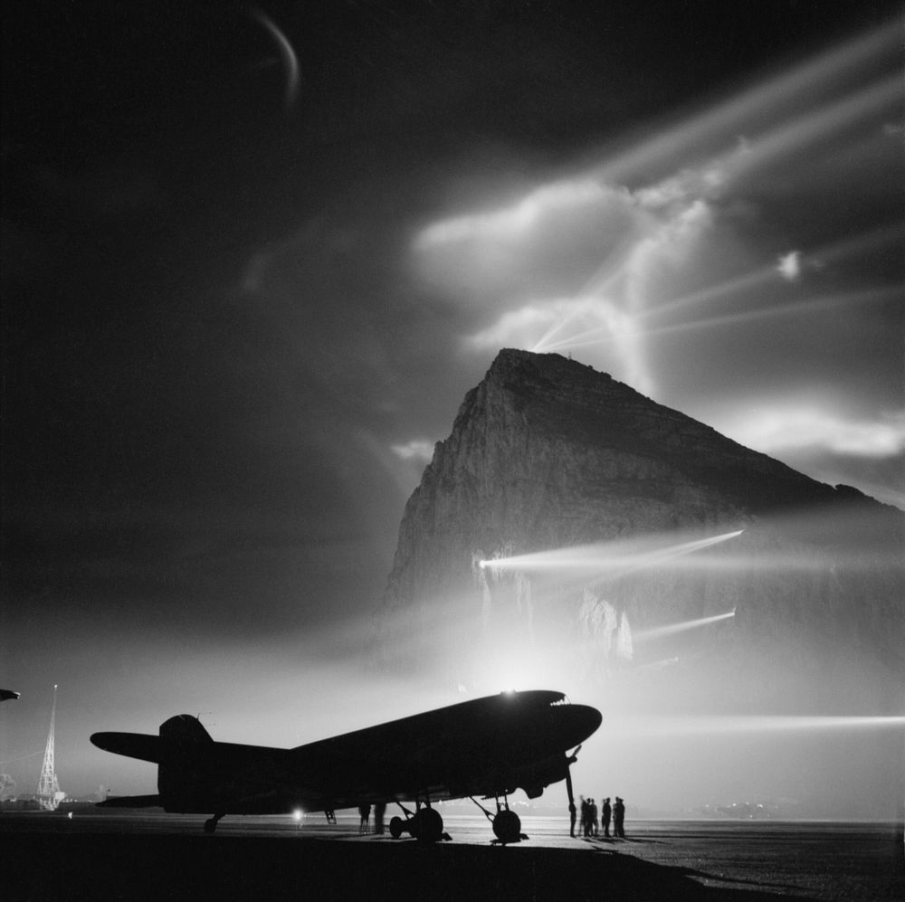 A Douglas Dakota of BOAC at Gibraltar, silhouetted by searchlights on the Rock.A Douglas Dakota of BOAC, silhouetted by…
