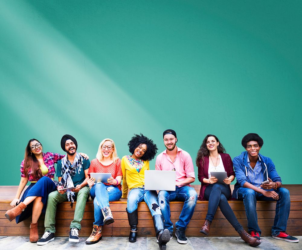 Diverse college students sitting in front of a green wall mockup
