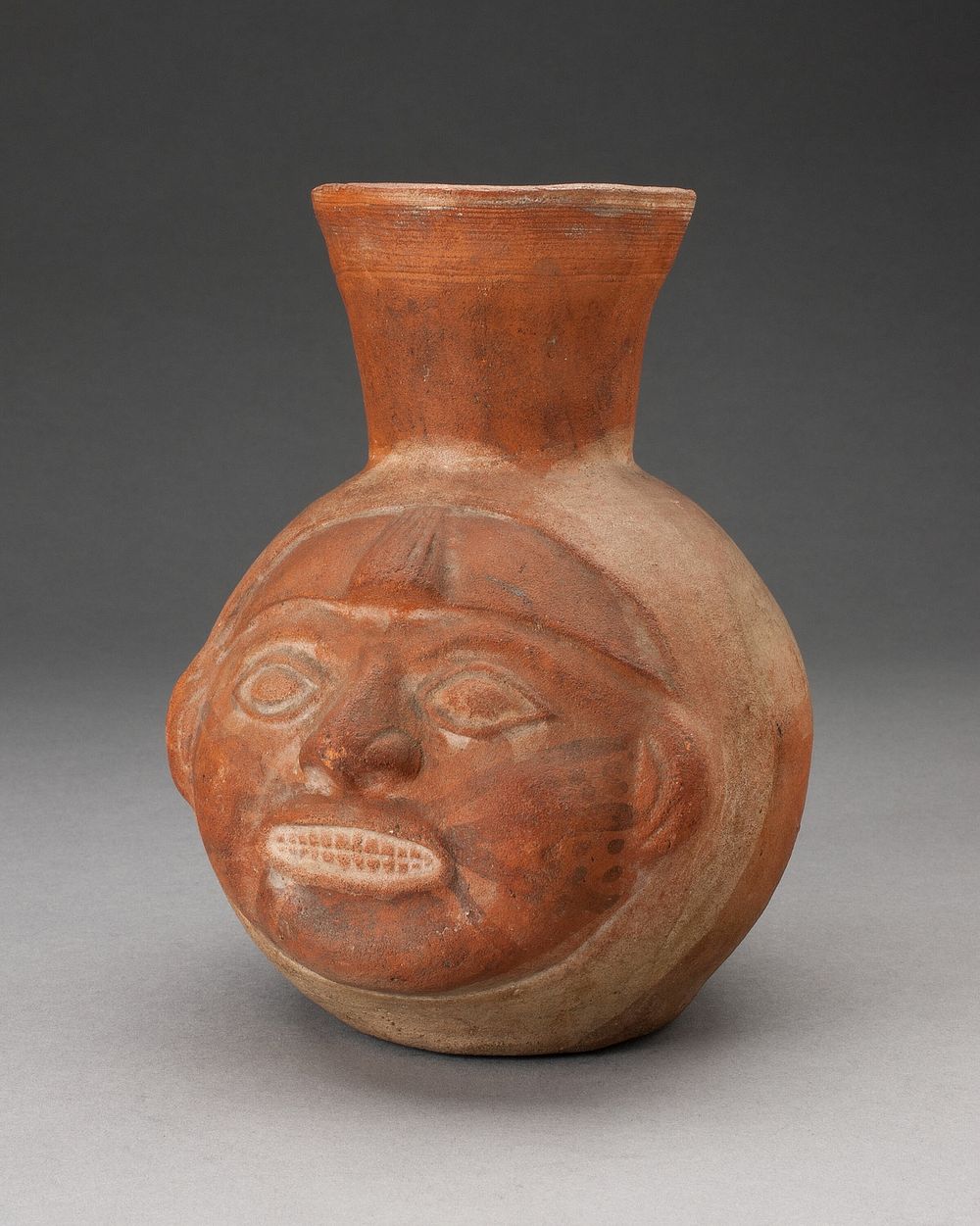 Jar in the Form of a Human Head with Face Painting and Showing Teeth by Moche