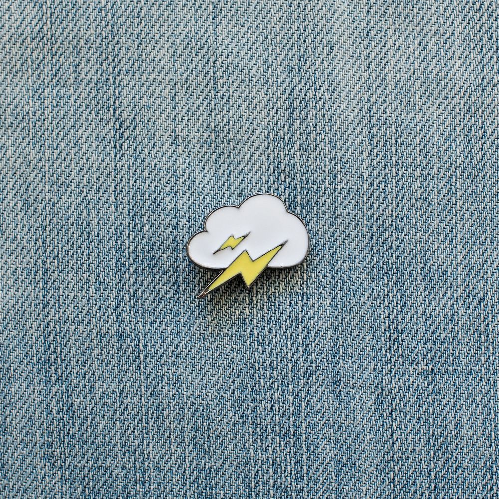 Lightning bolt enamel pin on denim close up.