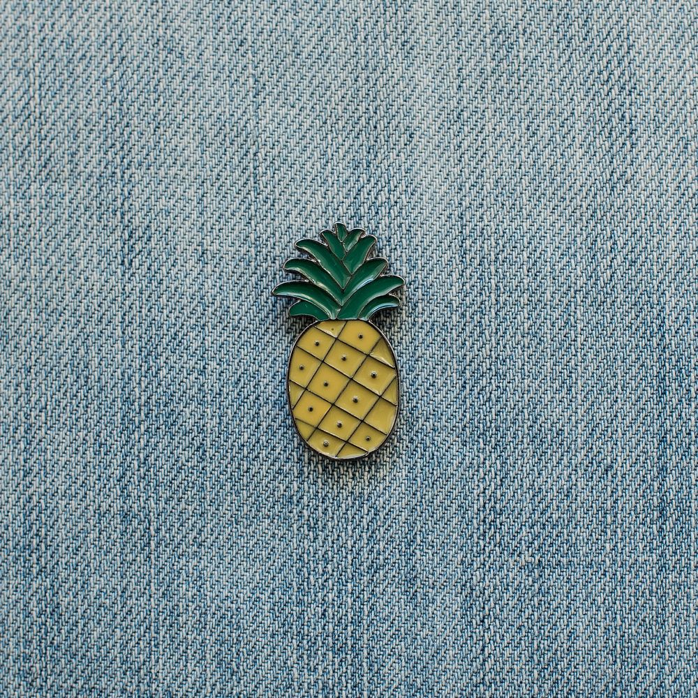 Pineapple lapel pin on denim close up.