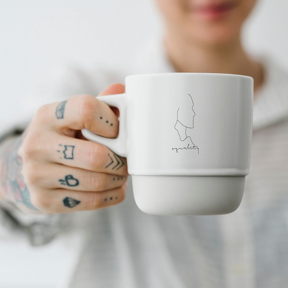 Tattooed woman holding a white coffee cup mockup