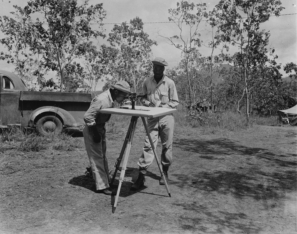 U.S. African American troops in New Guinea. Part of a surveying crew of a African American engineer unit. The two men shown…