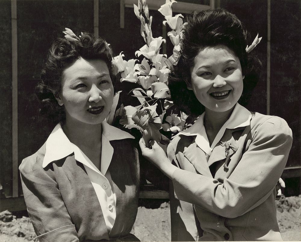 Japanese relocation, California. Nancy Kawashimo (left), and Emiko Hino, both from Los Angeles, arrange paper flowers for…