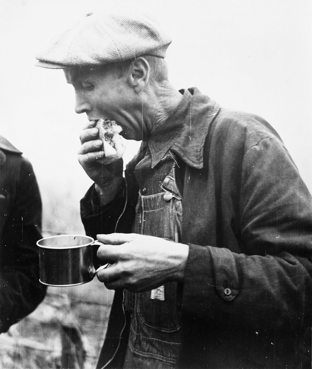 Farmer eats hamburger at cornhusking contest, Marshall County, Iowa. Sourced from the Library of Congress.
