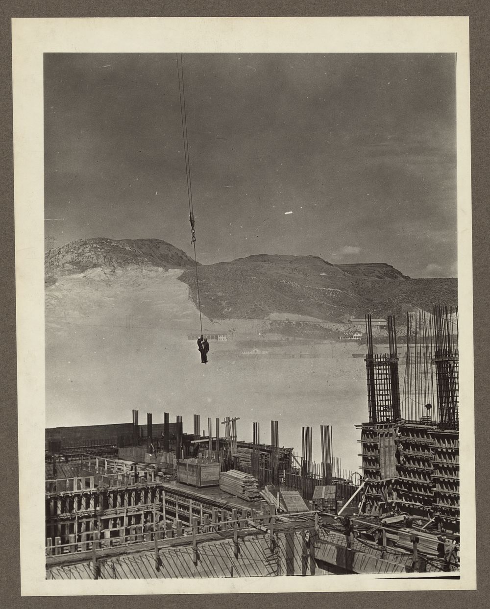 Grand Coulee Dam, Columbia Basin Reclamation Project, Wash. Two riggers on a hook on their way to work at the powerhouse on…