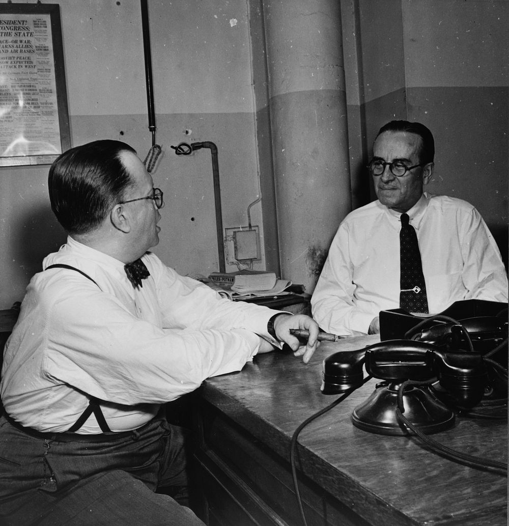 New York, New York. Newsroom of the New York Times newspaper. James and McCaw conferring. Sourced from the Library of…
