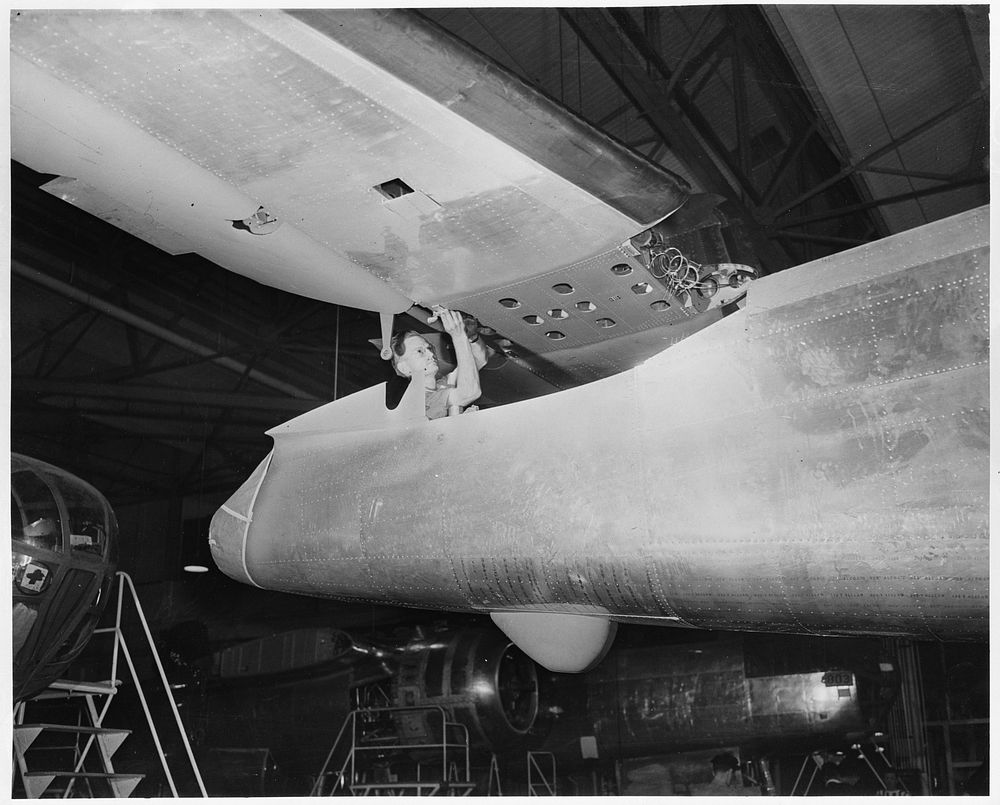The tail assembly for a North American B-25 bomber is lowered into place from an overhead crane on the final assembly floor.…