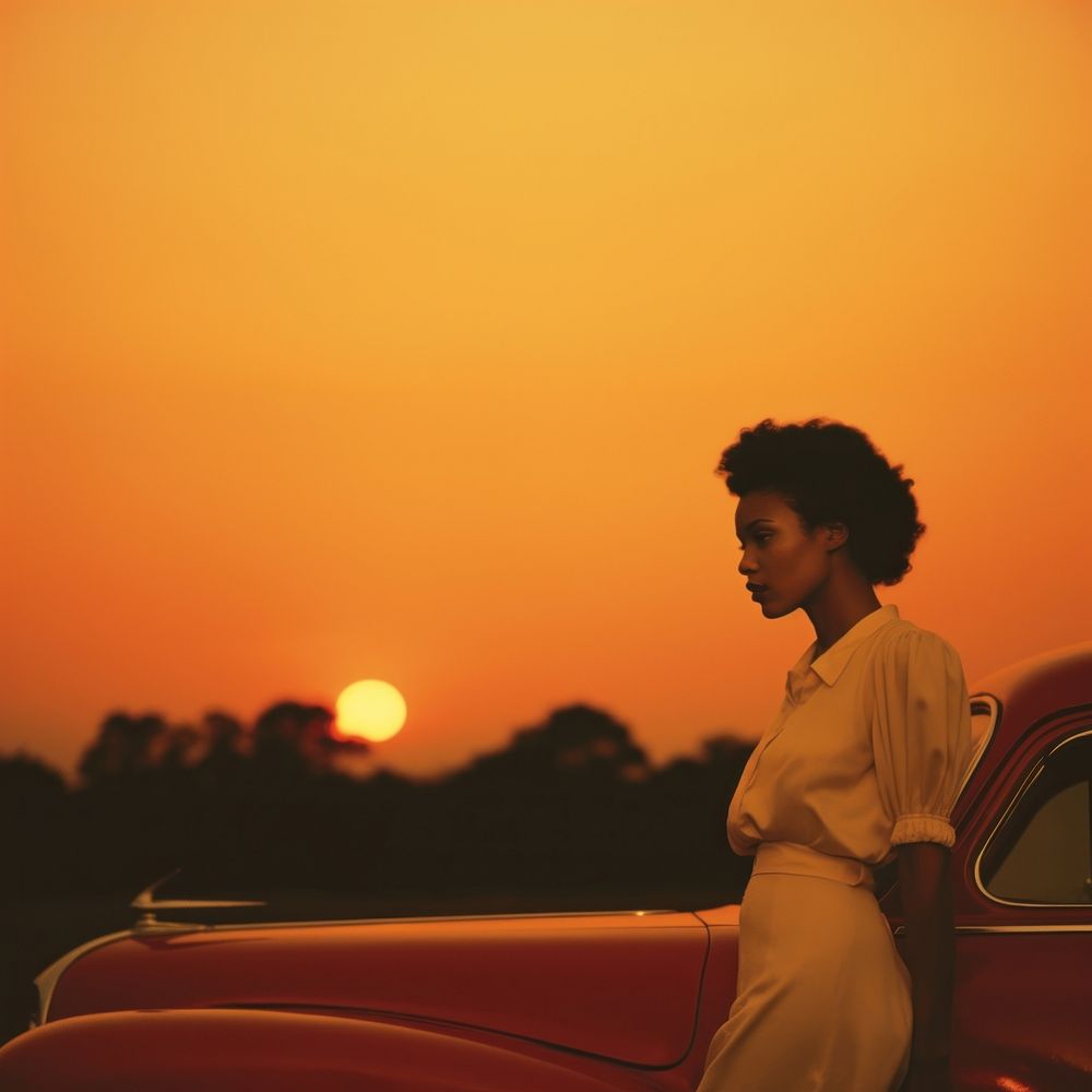 Woman standing by her car, sunset. 