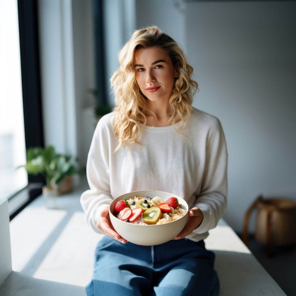 Woman eating a healthy bowl kitchen sitting. 