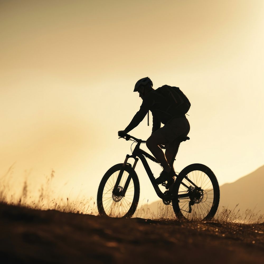 photo side view sillhuette of man riding a bicycle bike uphill with natural light. 