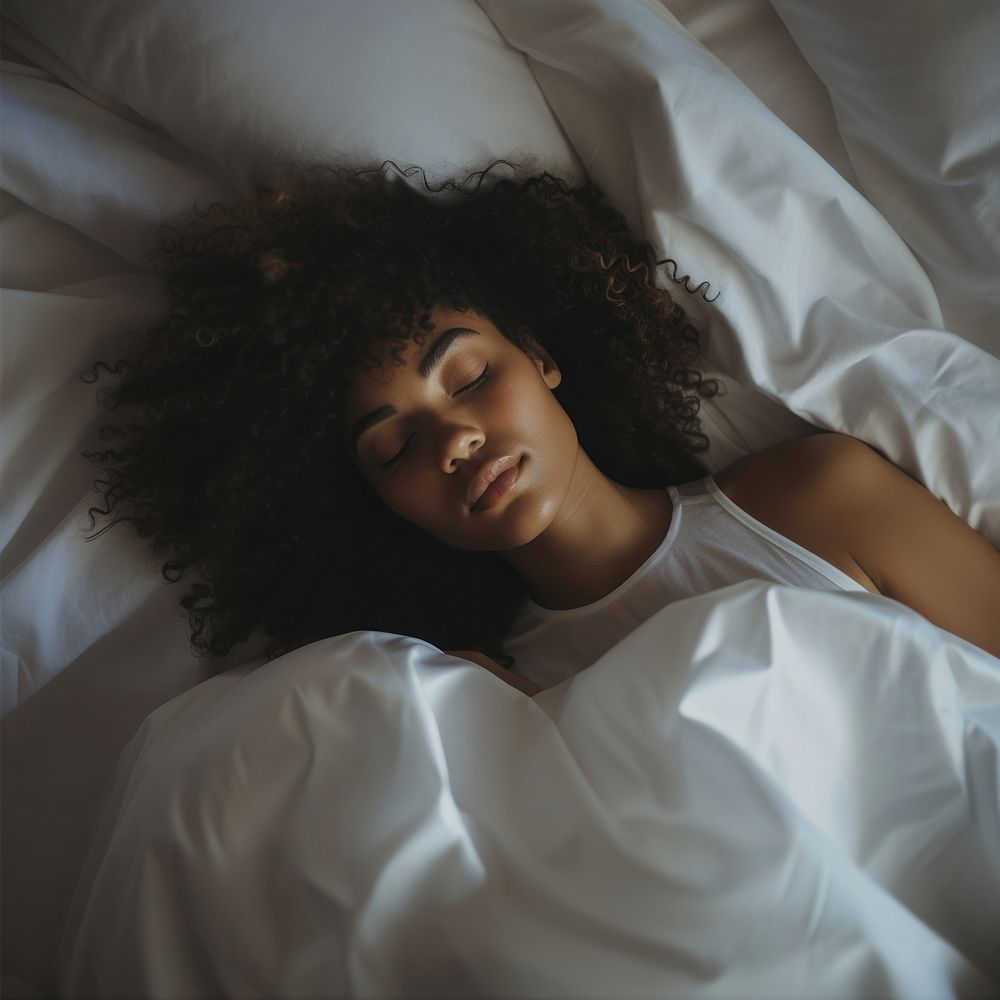 photos of a black woman lying on the side sleeping in white bed. 