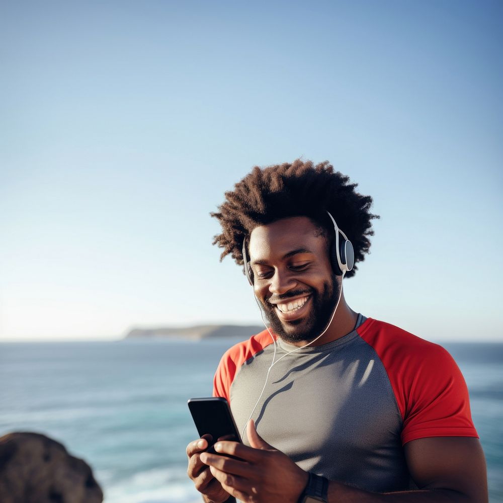 Photo of Portrait of a smiling afro-american sports man stretching his muscular arms before workout by the sea. AI generated…