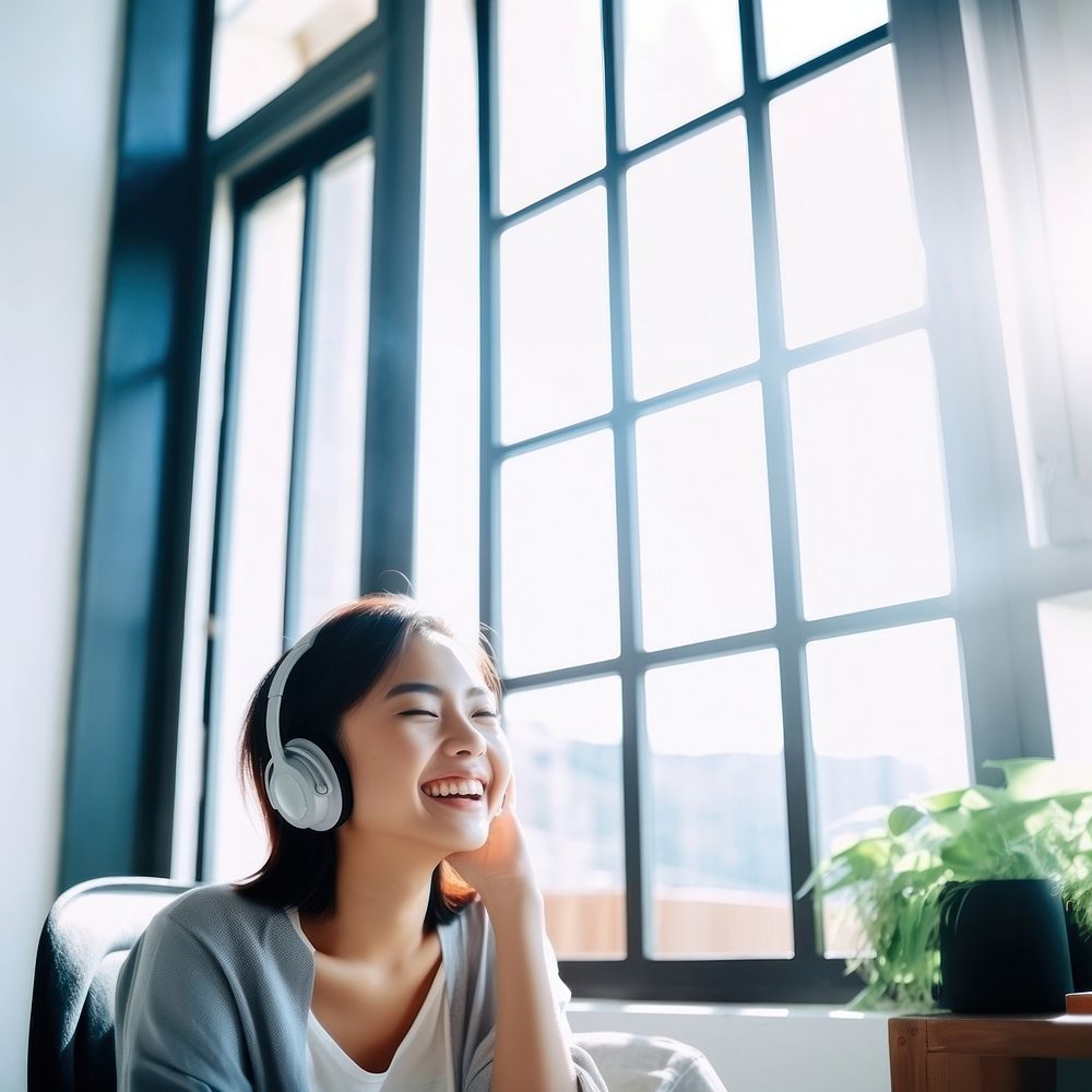 Photo of Asian woman smiling at home in headphones.  