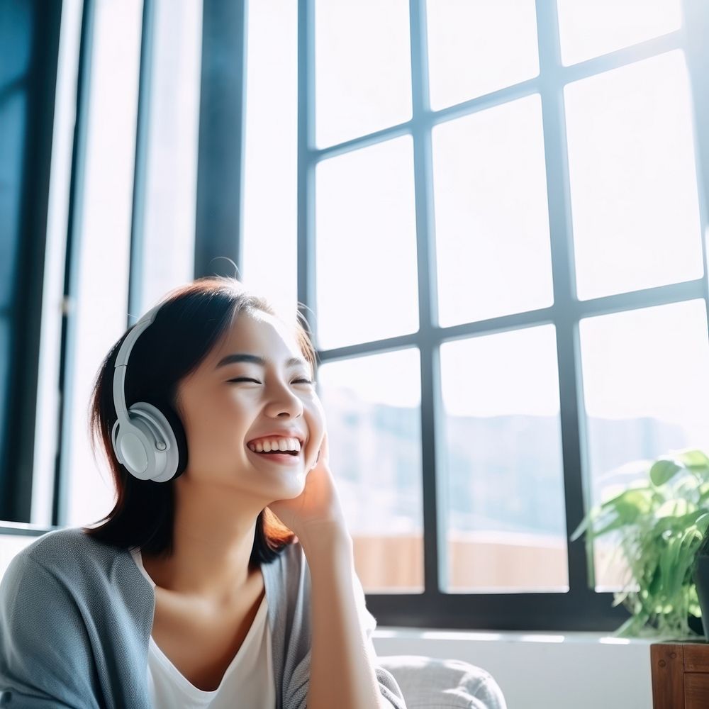 Photo of Asian woman smiling at home in headphones.  